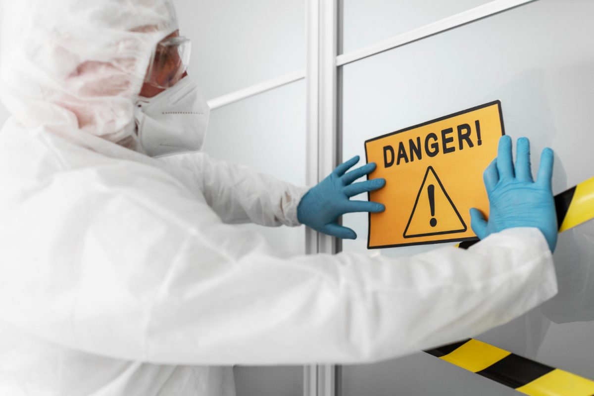 Technicien en combinaison blanche posant un panneau Danger lors d'une intervention de désamiantage extérieur à Lyon